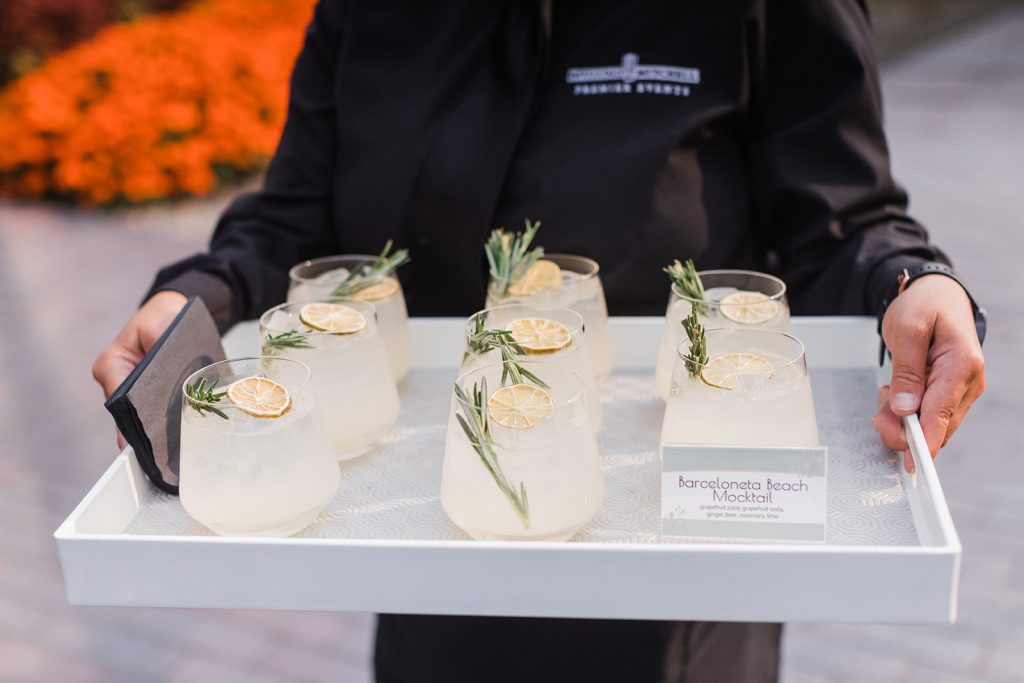 Barcelona Beach Mocktails, zero-proof summer beverage, on party tray of cocktails held by Cameron Mitchell Premier Events catering server.