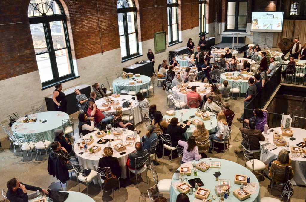 Corporate style meeting with podium stage and round tables in place at The Stack at Municipal Light Plant.